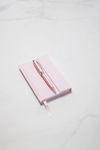 Pink Notebook and Pen on White Marble Surface