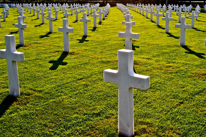 Rows of white crosses in a military cemetery on green grass