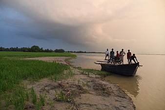 Men with motorcycle on boat near riverbank during storm