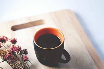 Black Coffee Cup with Orange Interior on Wooden Board