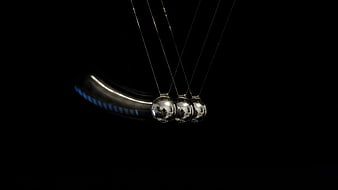 Newton's Cradle in Motion Against Black Background