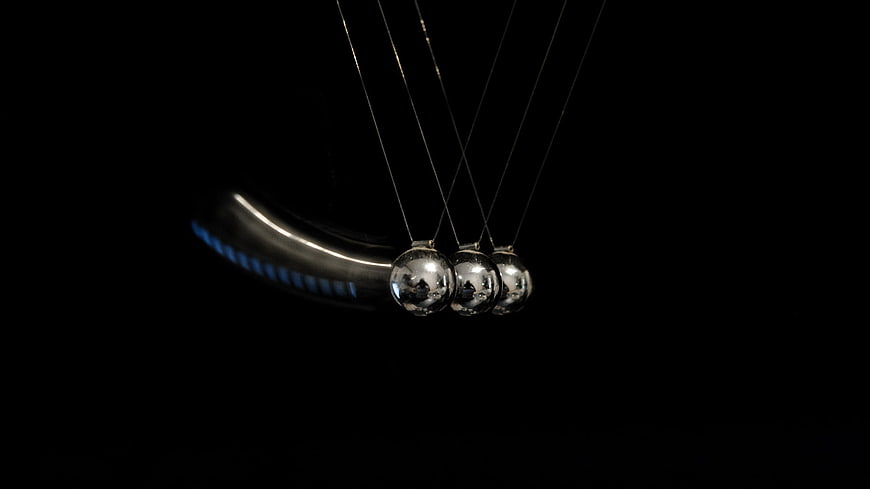 Newton's Cradle in Motion Against Black Background