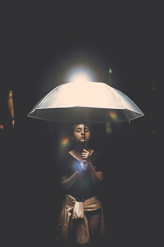Woman holding umbrella with dramatic backlighting