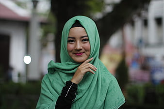 Portrait of a smiling Asian woman wearing a green hijab outdoors