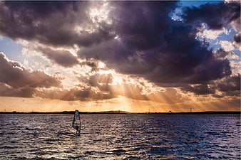 Windsurfer Silhouette Against Dramatic Sunset Sunbeams