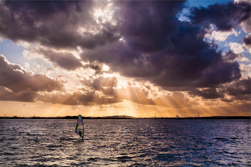 Windsurfer Silhouette Against Dramatic Sunset Sunbeams