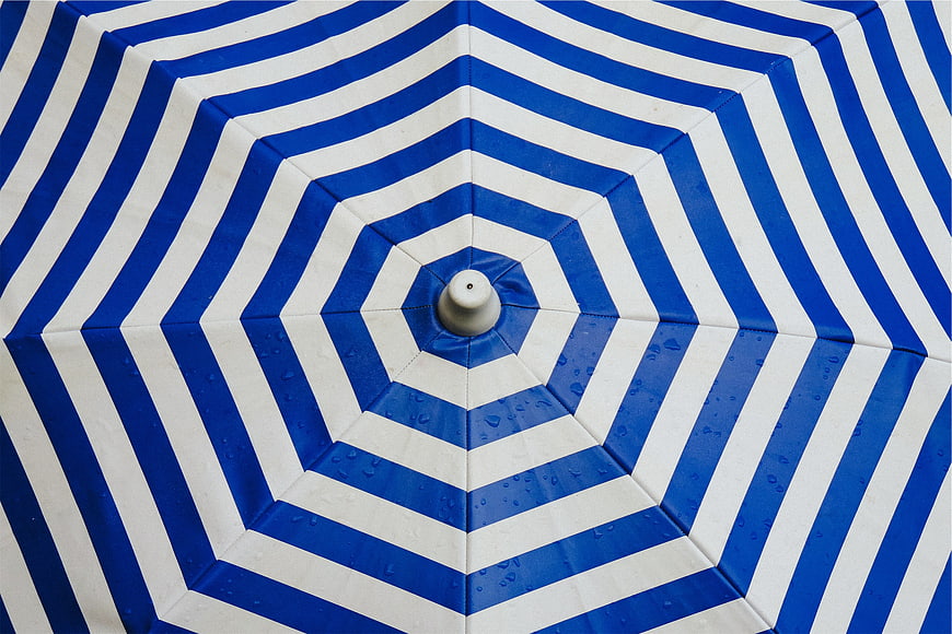 Blue and white striped beach umbrella top view
