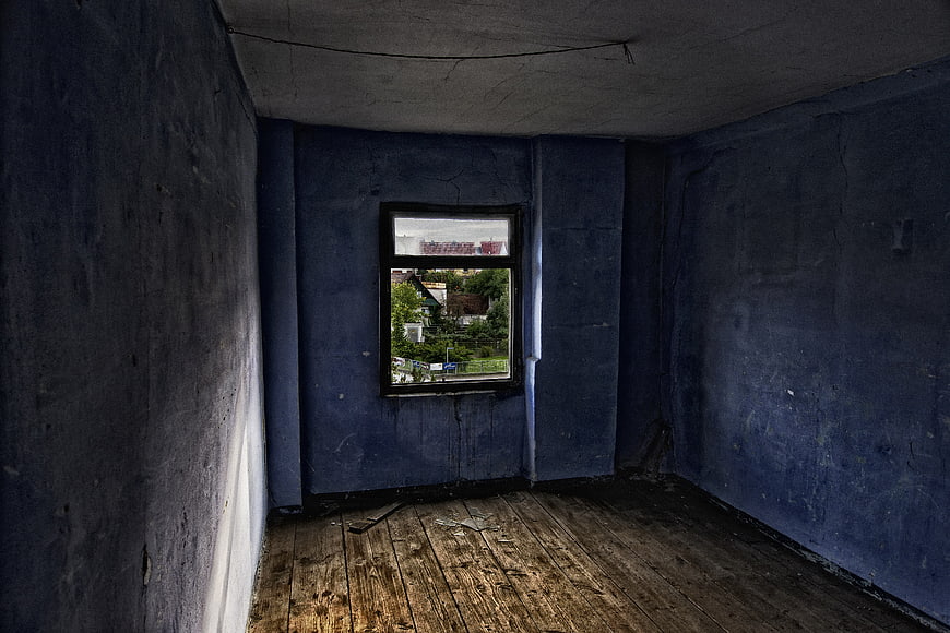Empty abandoned room with blue walls and wooden floor