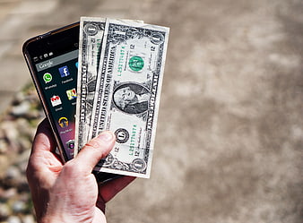 Hand holding smartphone and US dollar bills