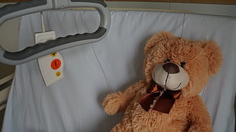 Teddy bear on hospital bed with call button