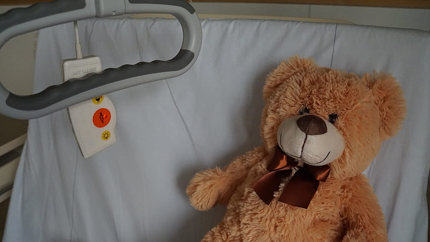 Teddy bear on hospital bed with call button