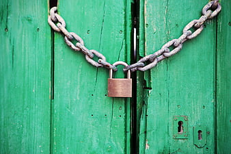 Rusty Chain and Padlock Securing Weathered Green Wooden Gate