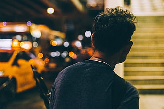 Man from behind on city street at night with bokeh lights