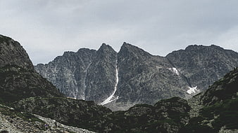 Majestic Rocky Mountain Peaks with Snow Patches and Hikers