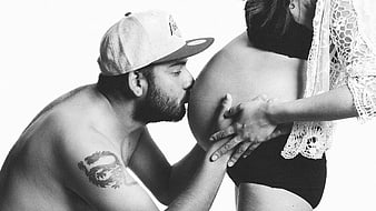 Black and White Photo of Man Kissing Pregnant Belly