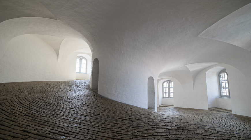 White vaulted interior with cobblestone floor and arched windows