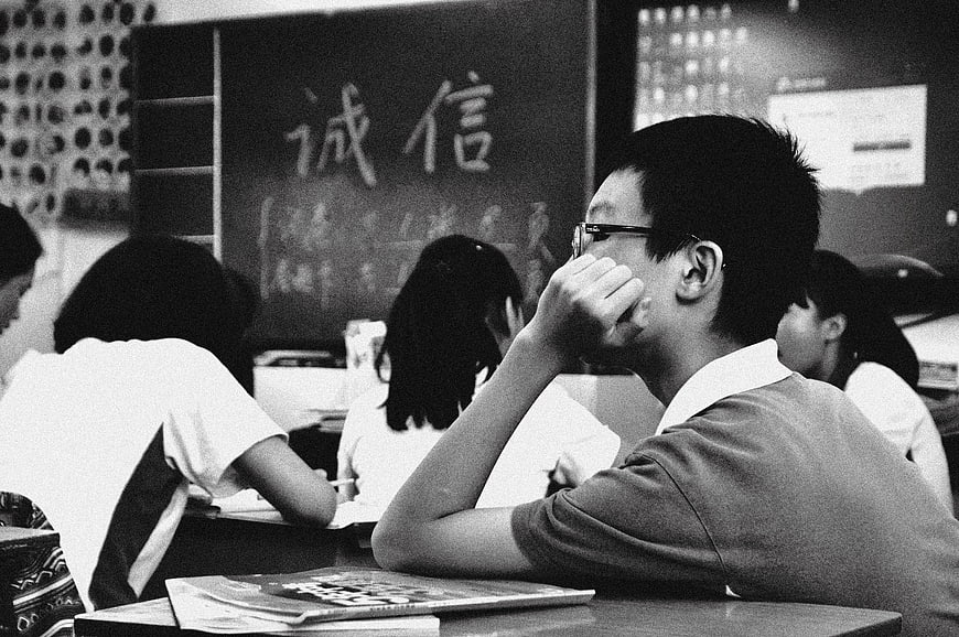 Sad student resting head on hand in classroom