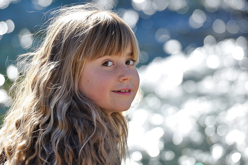 Portrait of a smiling girl with long wavy hair and freckles