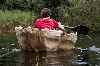 Boy paddling traditional coracle boat on calm river