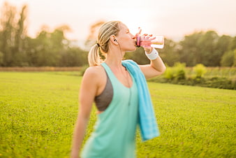 Woman drinking water after outdoor workout in park