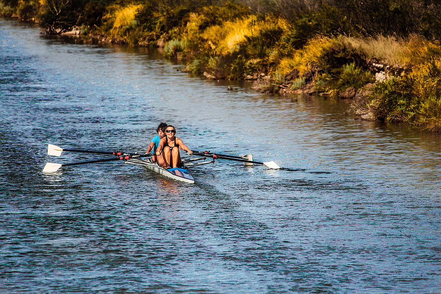 Two women rowing a double scull on a sunny river