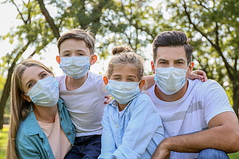 Family wearing face masks outdoors in a park