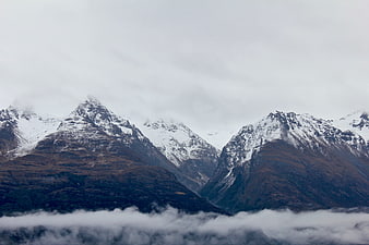 Snow-Capped Mountain Peaks Rising Above Clouds