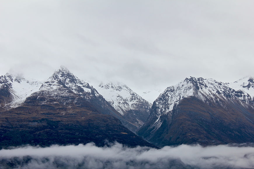 Snow-Capped Mountain Peaks Rising Above Clouds