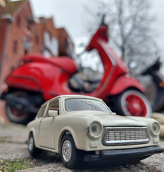 Vintage Trabant toy car with red scooter background