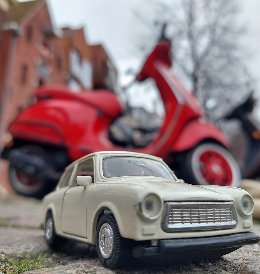 Vintage Trabant toy car with red scooter background