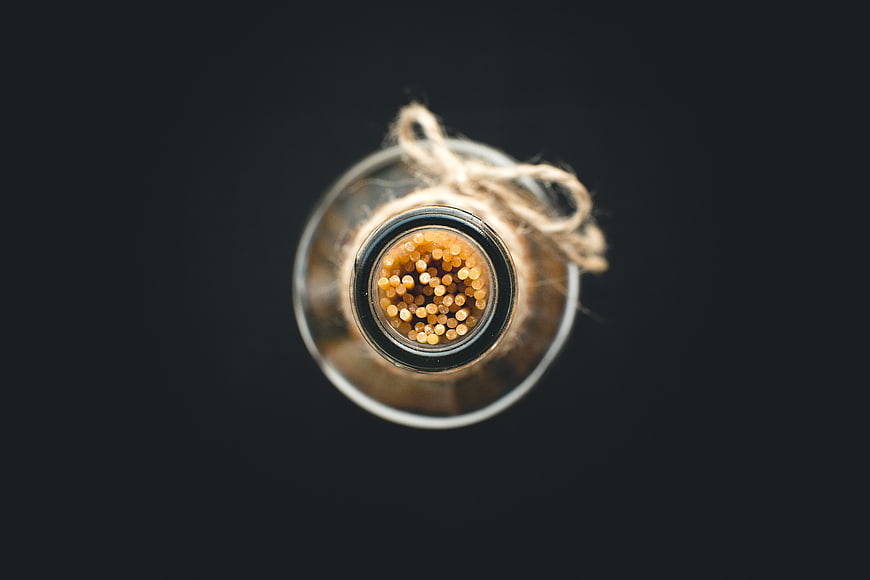 Top view of spaghetti in a glass bottle on black background