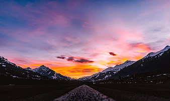 Dramatic Sunset Over Snowy Mountain Valley with Road