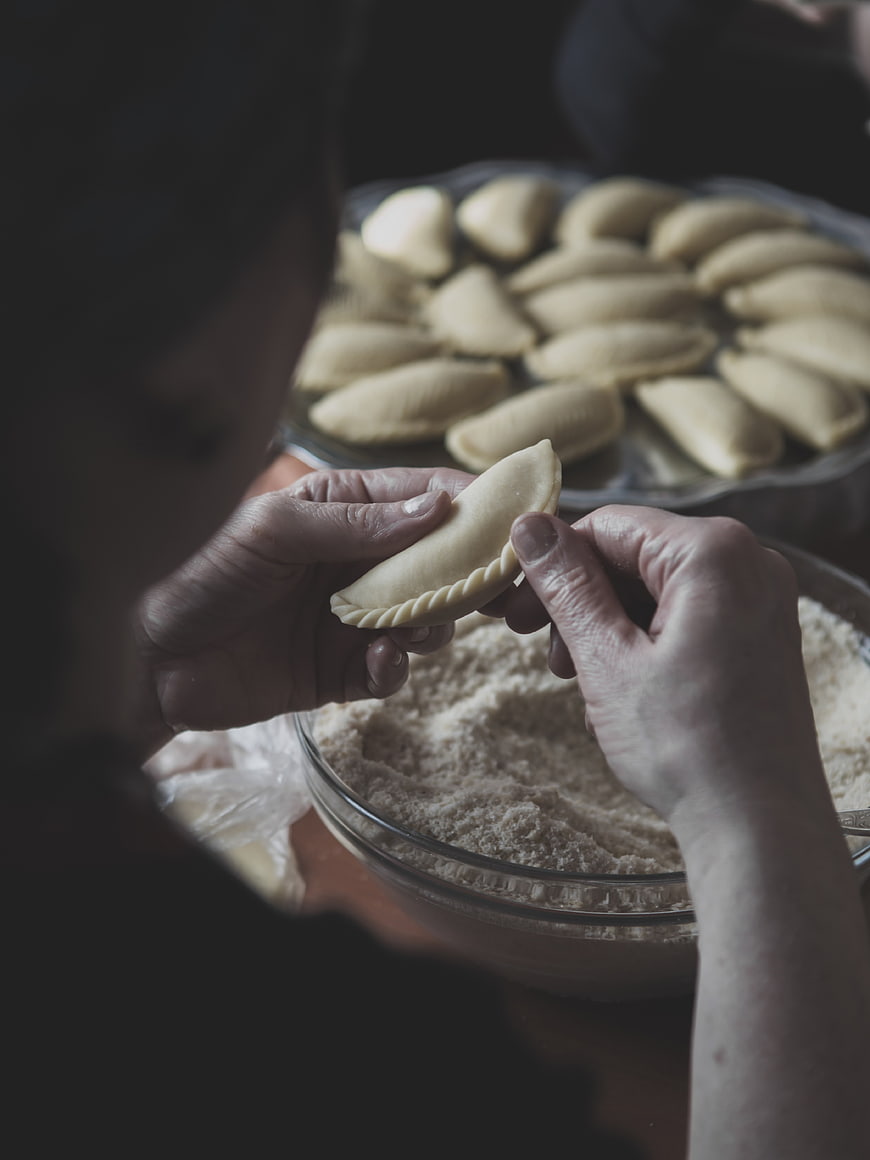 Hands shaping homemade ravioli dough with flour