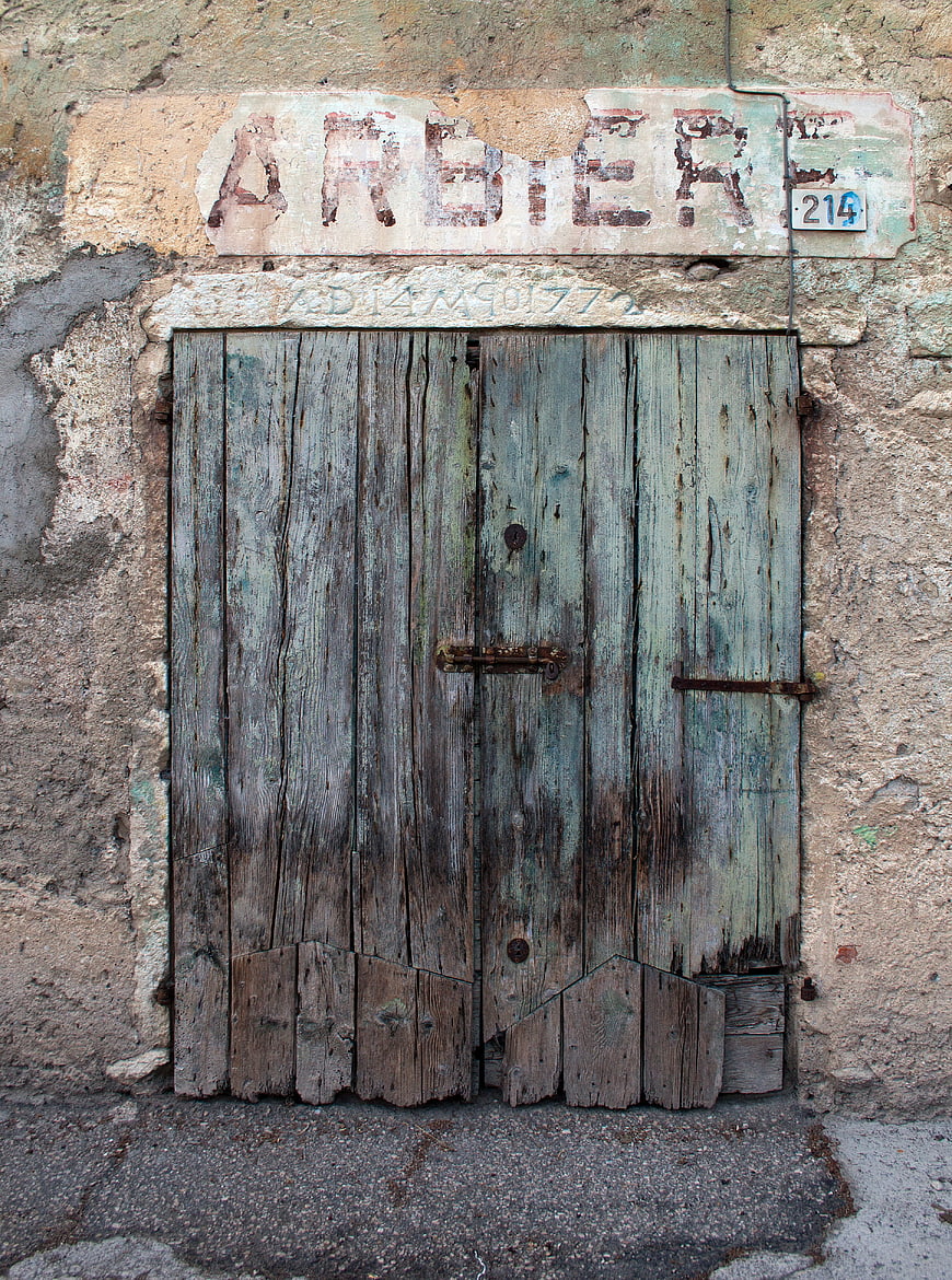 Weathered wooden door of an old barber shop with faded signage