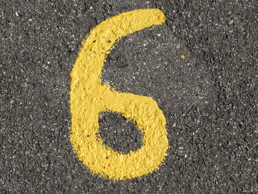 Yellow Number Six Painted On Dark Asphalt Road Surface