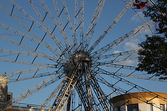 Low angle view of large steel ferris wheel against blue sky