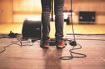 Musician legs on stage with guitar pedals and cables