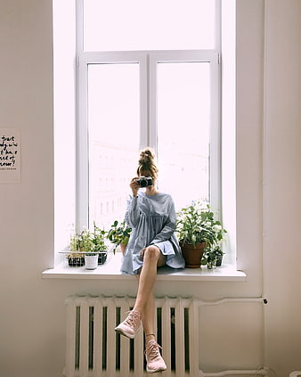 Woman with Camera Sitting on Window Sill with Plants