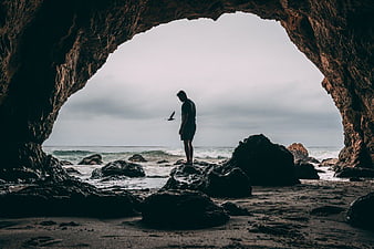 Man Standing in Sea Cave Looking at Ocean