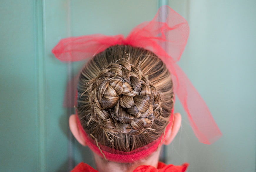 Back view of girl with braided bun and red bow