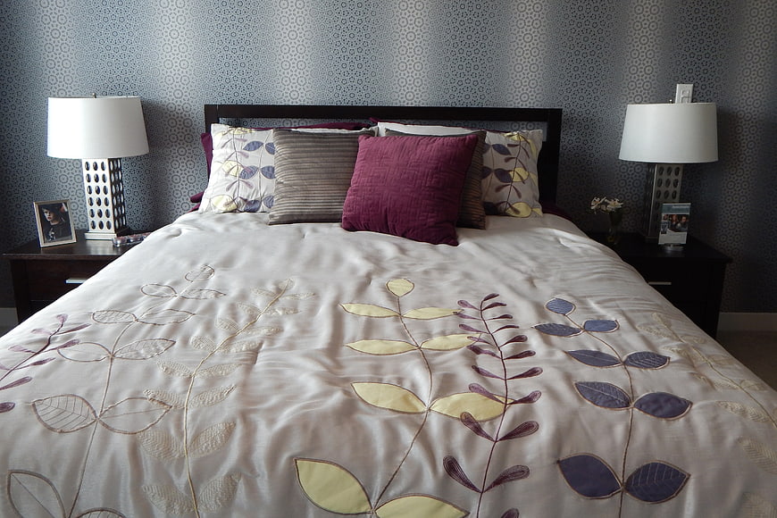 Cozy Bedroom Interior With Floral Bedding And Patterned Wallpaper