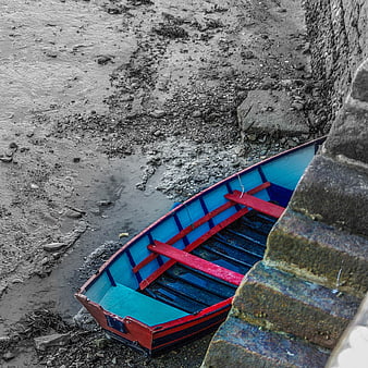 Colorful wooden boat on muddy shore at low tide