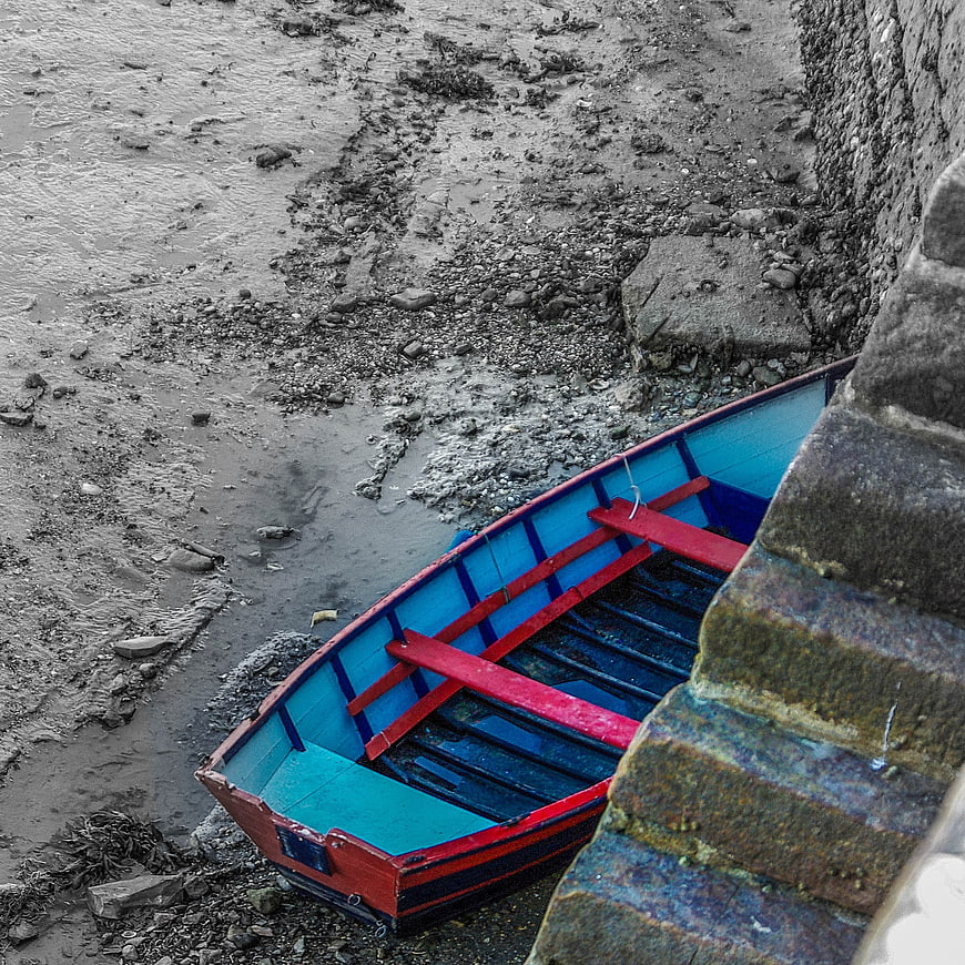 Colorful wooden boat on muddy shore at low tide