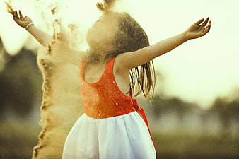 Child Playing in Sand with Arms Raised in Golden Hour Light
