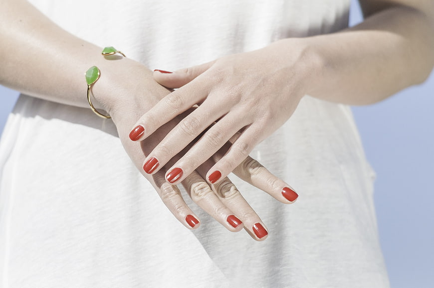 Close-up of hands with red manicure and green bracelet