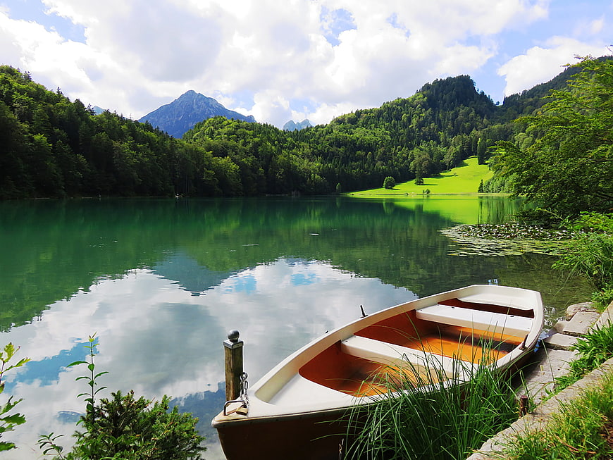 White rowboat docked at serene alpine lake with mountains