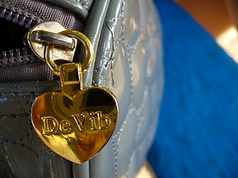 Close-up of gold heart charm on gray quilted bag