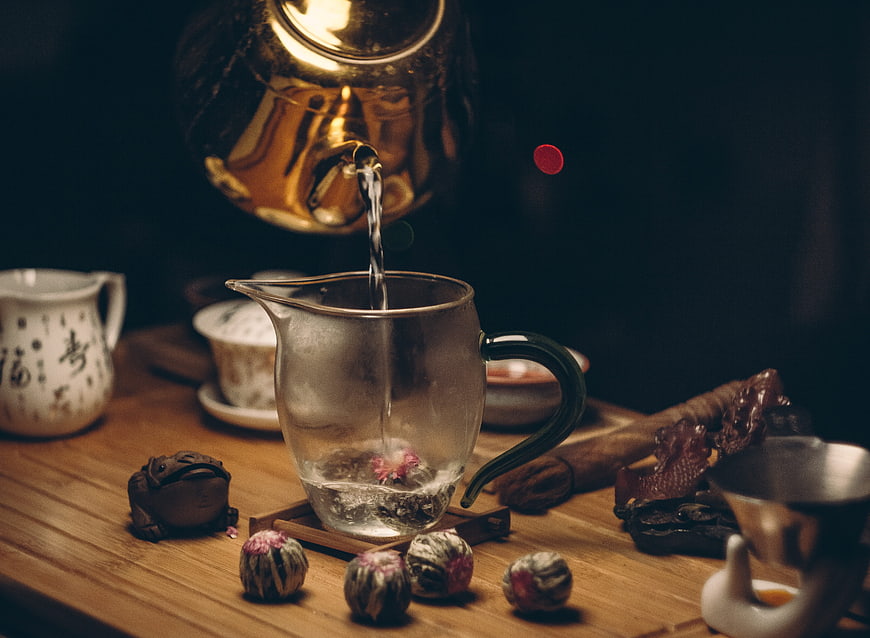 Pouring Hot Water into Glass Teapot with Tea Balls