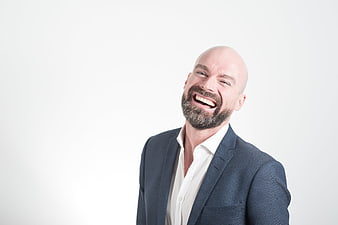 Laughing bald businessman in blue suit on white background