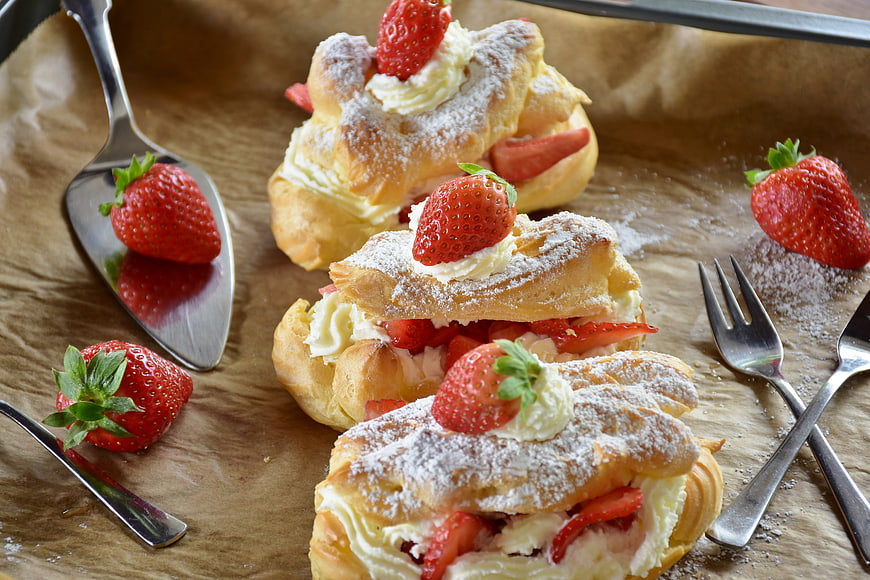 Strawberry cream pastries on brown paper with silverware